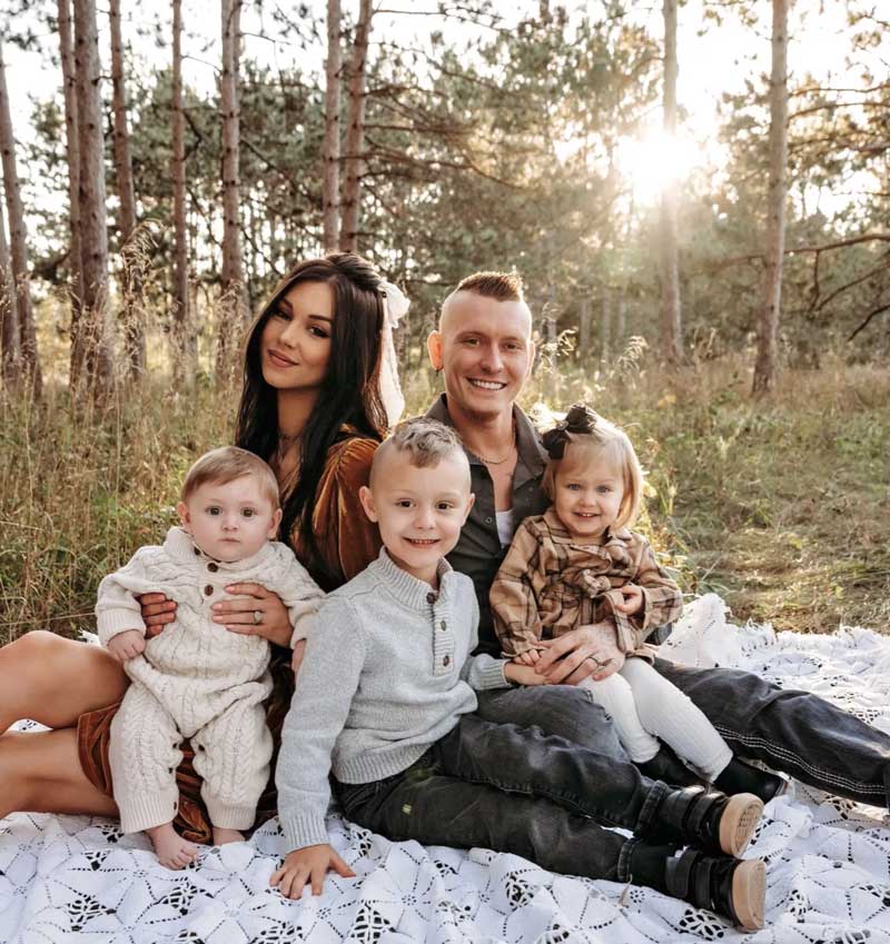 Family of five sitting on blanket in forest